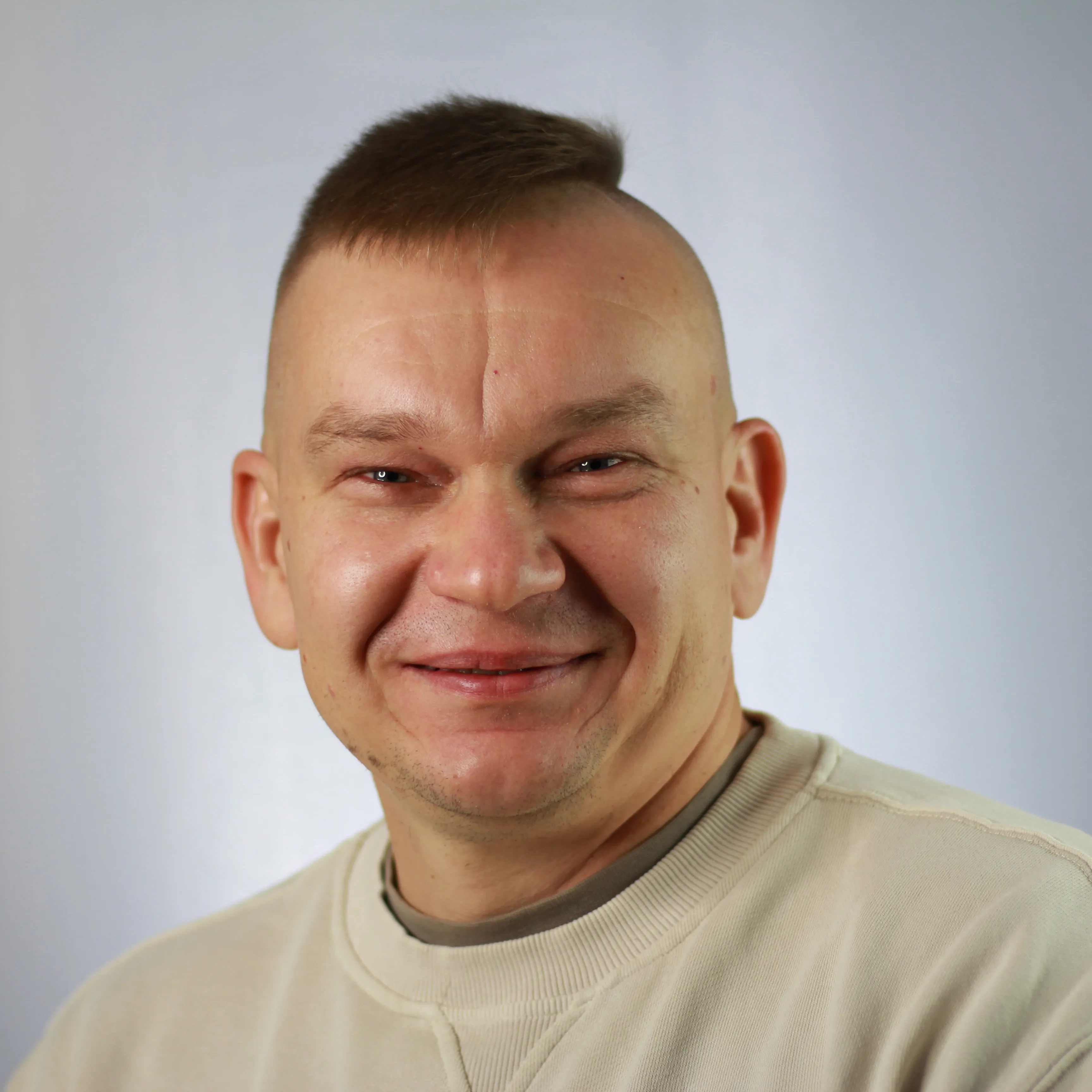 Porträtfoto von Pfarrer Ivan Shirokov vor hellem Hintergrund. Er trägt ein helles Sweatshirt und lächelt in die Kamera.